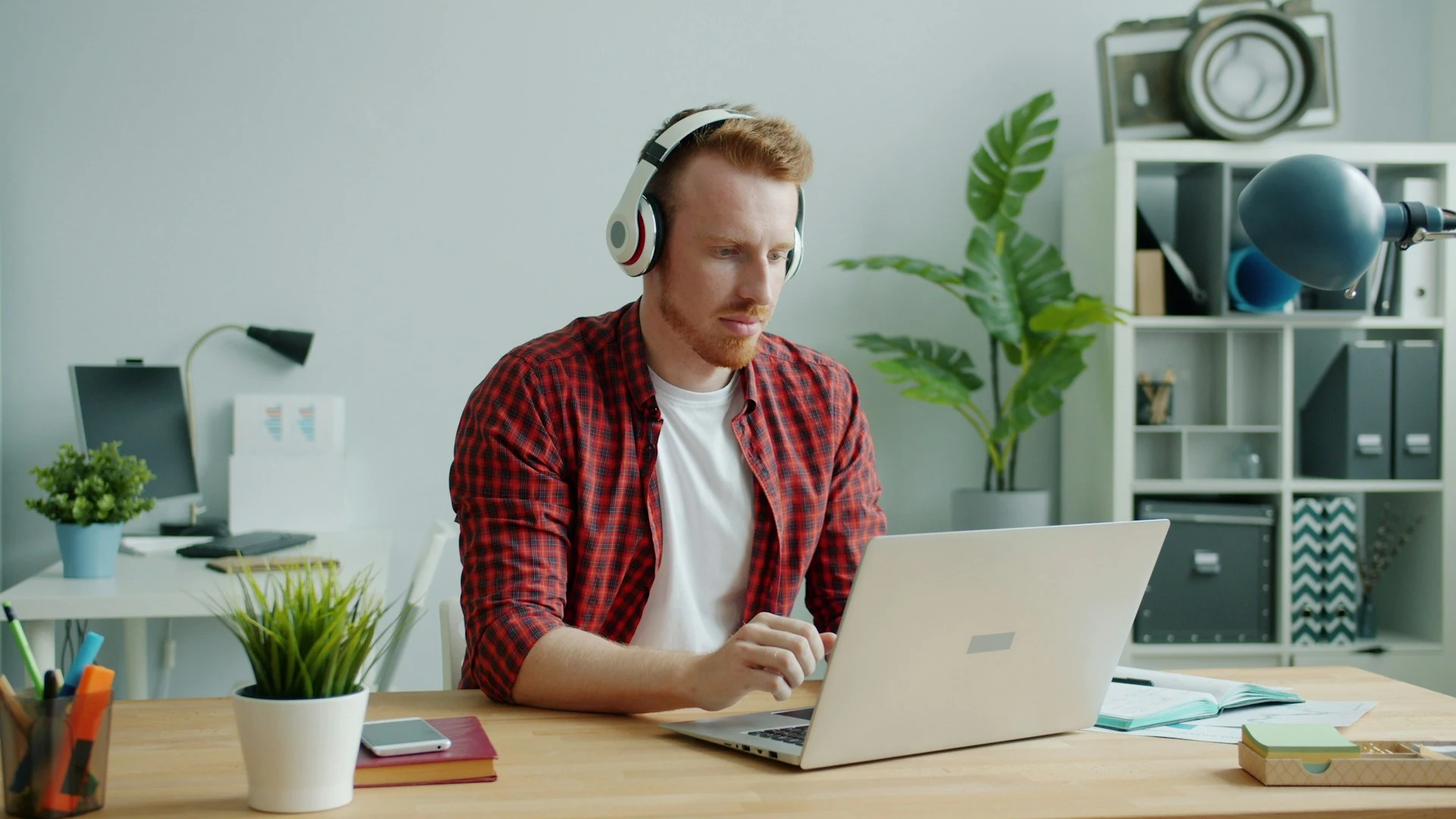 Man wearing headphones working on a laptop at a desk.